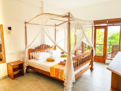 a bedroom with a canopy bed in a room at Twenty- Two Swiss Residence in Weligama
