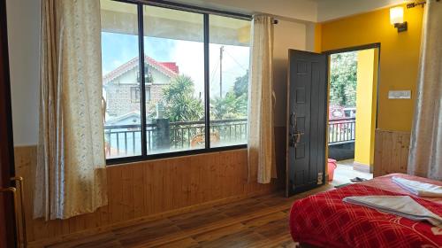 a bedroom with a bed and a large window at Bayaroo Stay Lamahatta in Darjeeling