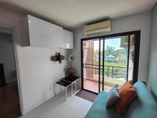 a living room with a blue couch and a balcony at Blue and green Farang homes in Chiang Mai