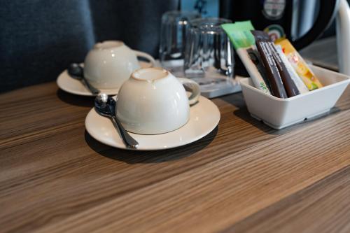 two tea cups on a table with a bowl of books at A Hotel Cozy in Ban Pa Sak
