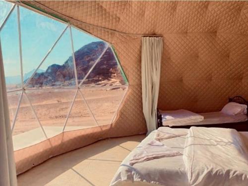 a bedroom with a view of the desert from a window at Wadi Rum The ARC camp in Wadi Rum