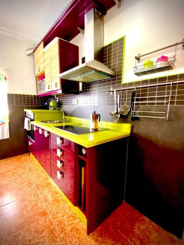 a kitchen with a yellow counter and red cabinets at Villasultana 1 in Chipiona