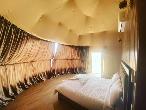 a bedroom with a large bed with a large ceiling at Wadi Rum The ARC camp in Wadi Rum