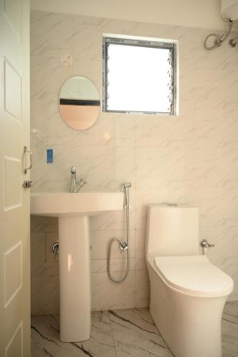 a bathroom with a toilet and a sink and a window at Bayaroo Stay Lamahatta in Darjeeling