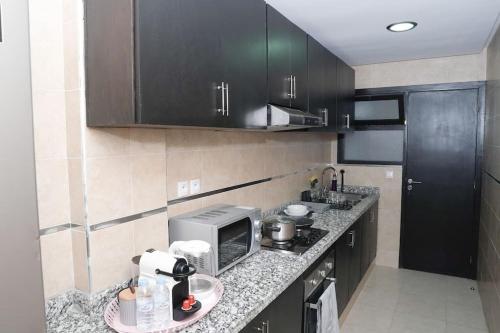 a kitchen with black cabinets and a counter top at Appartement Moderne au Cœur de Rabat in Océan