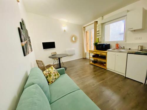 un salon avec un canapé vert et une cuisine dans l'établissement Le Bali, Magnifique T2, centre ville 1 er etage, à Valence