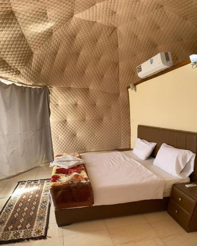 a bedroom with a bed and a wall at Wadi Rum The ARC camp in Wadi Rum