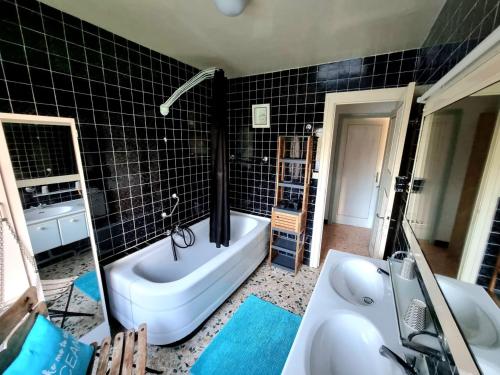 une salle de bain carrelée noire avec une baignoire et une baignoire dans l'établissement Parenthèse Océane Suite calme 1 ou 2 chambres entre bois et mer, à Perros-Guirec