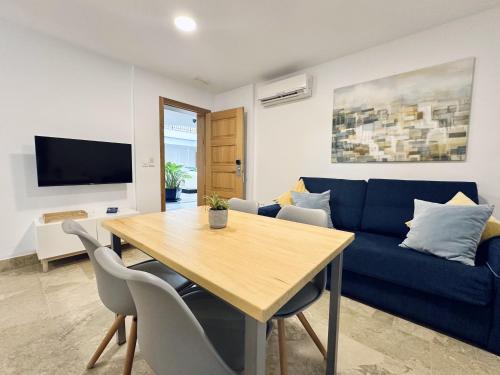 a living room with a blue couch and a wooden table at Hotel Apartamentos Marina Luz in Chipiona