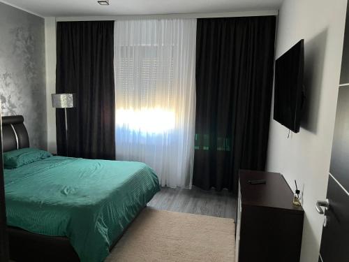 a bedroom with a green bed and a window at Apartament D&D in Piteşti