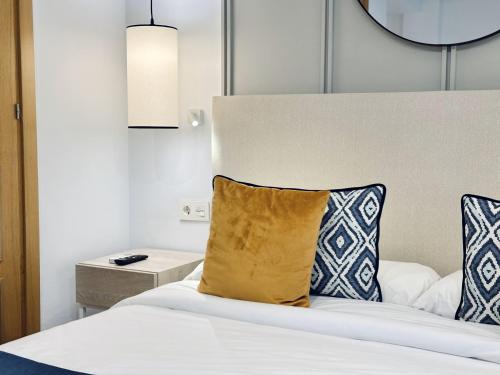 a bedroom with a bed with a yellow pillow on it at Hotel Apartamentos Marina Luz in Chipiona