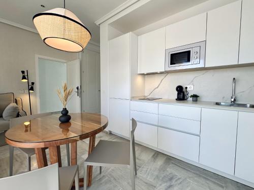 a kitchen with white cabinets and a wooden table at Hotel Apartamentos Marina Luz in Chipiona