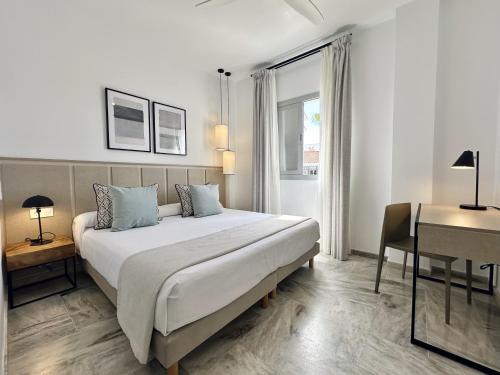 a bedroom with a large bed with a desk and a bed sidx sidx sidx sidx at Hotel Apartamentos Marina Luz in Chipiona