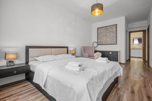 a bedroom with a large white bed with towels on it at ArtMob Apartment Isaran in Braşov