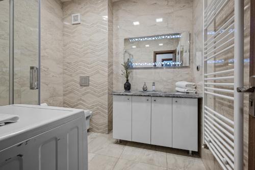 a white bathroom with a sink and a mirror at ArtMob Apartment Isaran in Braşov