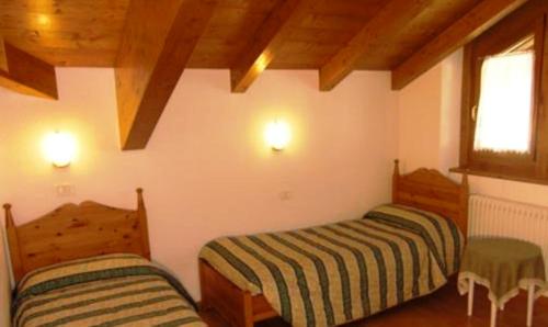 two beds in a room with wooden ceilings at Residence Il Giardino in Croviana