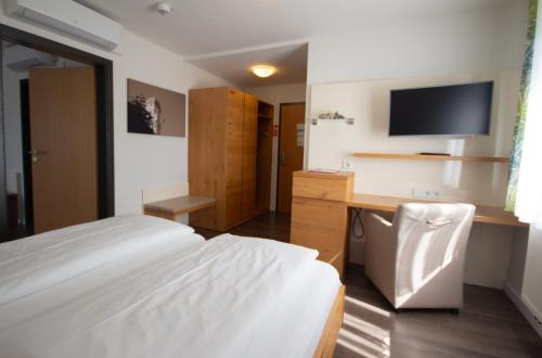 a bedroom with a bed and a desk and a television at Hotel Lipprandt in Wasserburg