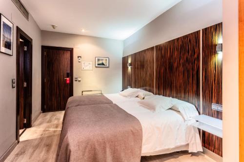 a bedroom with a large bed with a wooden wall at Hotel Gran Via in Zaragoza