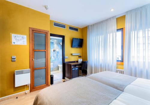 a bedroom with a bed and a desk with a television at Hotel Gran Via in Zaragoza