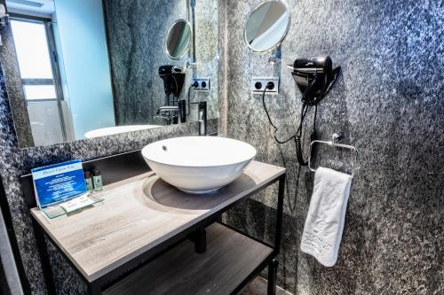 a bathroom with a white bowl sink on a counter at Hotel Gran Via in Zaragoza