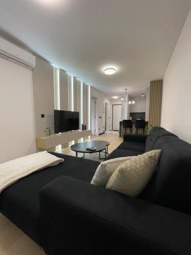 a living room with a black couch and a table at Apartman1105 Sarajevo Free Garage in Sarajevo