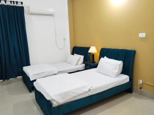 two beds in a hospital room with blue chairs at Victoria Guest House in Bahawalpur