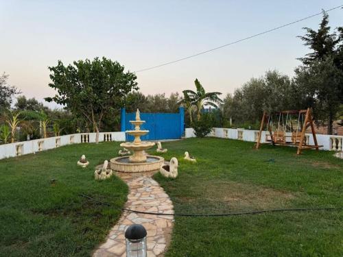 a fountain in the middle of a yard with a playground at le petit paradis in Chaba Remada