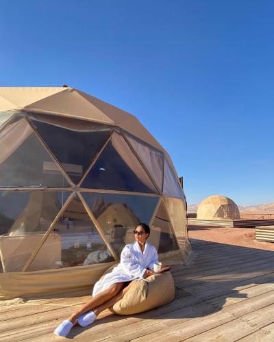 a woman laying in front of a tent at Wadi Rum The ARC camp in Wadi Rum