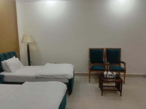 a hotel room with two beds and a chair at Victoria Guest House in Bahawalpur
