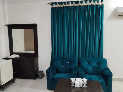 a living room with a blue couch and a table at Victoria Guest House in Bahawalpur
