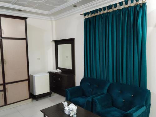 a living room with a blue couch and a table at Victoria Guest House in Bahawalpur