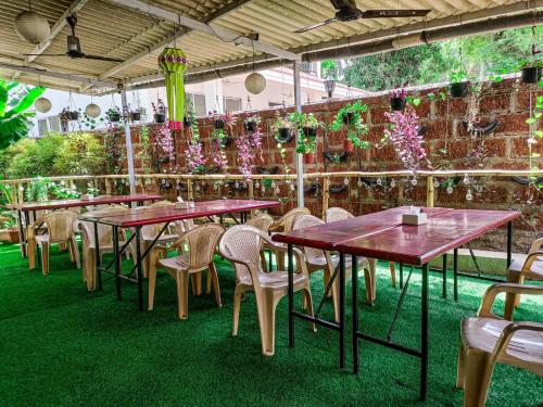 a row of tables and chairs in a patio with plants at Bhumi Holiday Home in Alibaug