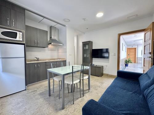 a kitchen and living room with a table and a couch at Hotel Apartamentos Marina Luz in Chipiona