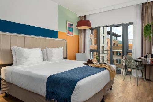 a hotel room with a large bed and a desk with a table at Neighbourgood Newlands in Cape Town