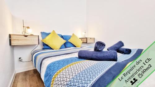 une chambre avec un lit avec des oreillers bleus et jaunes dans l'établissement Les Suites Mulhousiennes - Charme & Sérénité, à Mulhouse