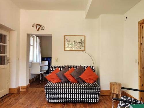 a living room with a black and white couch with orange pillows at Ferienwohnungen Hermannsmuehle in Klausdorf