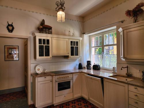 a kitchen with white cabinets and a sink and a window at Ferienwohnungen Hermannsmuehle in Klausdorf