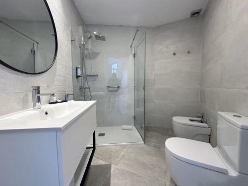 a bathroom with a sink and a toilet and a mirror at Hotel Apartamentos Marina Luz in Chipiona