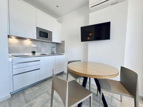 a kitchen with a wooden table and chairs in a room at Hotel Apartamentos Marina Luz in Chipiona