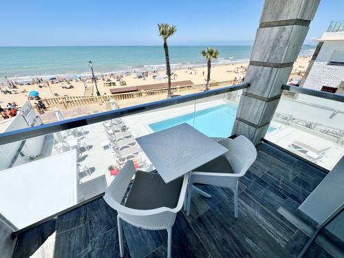 a balcony with a table and chairs and the beach at Hotel Apartamentos Marina Luz in Chipiona