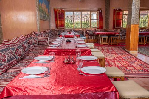 a long dining room with red tables and chairs at Hotel Awayou in Bou Tharar