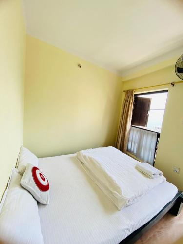 a bedroom with a bed with white sheets and a window at Diya's Guest House - Family Environment in Bandīpur
