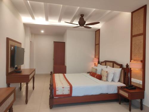 a bedroom with a bed with a ceiling fan and a television at Mohor Kutir Resorts in Bolpur