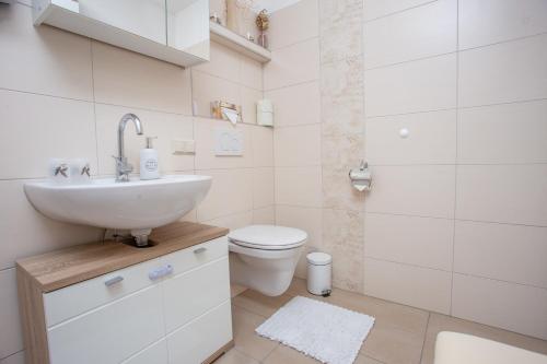 a white bathroom with a sink and a toilet at Schnelli Appartement Schladming in Schladming
