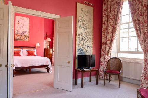 a bedroom with red walls and a bed and a tv at Dukes Bath in Bath