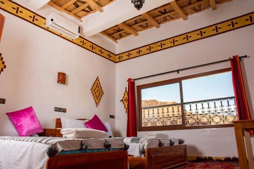 a bedroom with two beds and a large window at Hotel Awayou in Bou Tharar