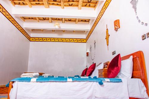 a bedroom with a bed with red pillows at Hotel Awayou in Bou Tharar