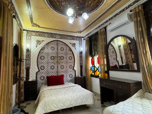 a bedroom with a bed with a red pillow at Riad Mogador in Meknès