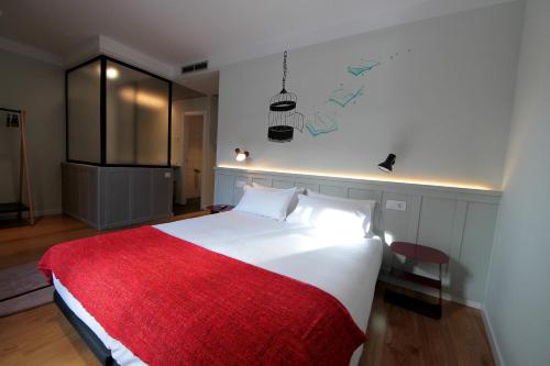 a bedroom with a large white bed with a red blanket at H Complutum in Alcalá de Henares