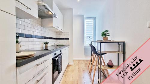 une cuisine avec des placards blancs et un comptoir dans l'établissement Les Suites Mulhousiennes - Charme & Sérénité, à Mulhouse